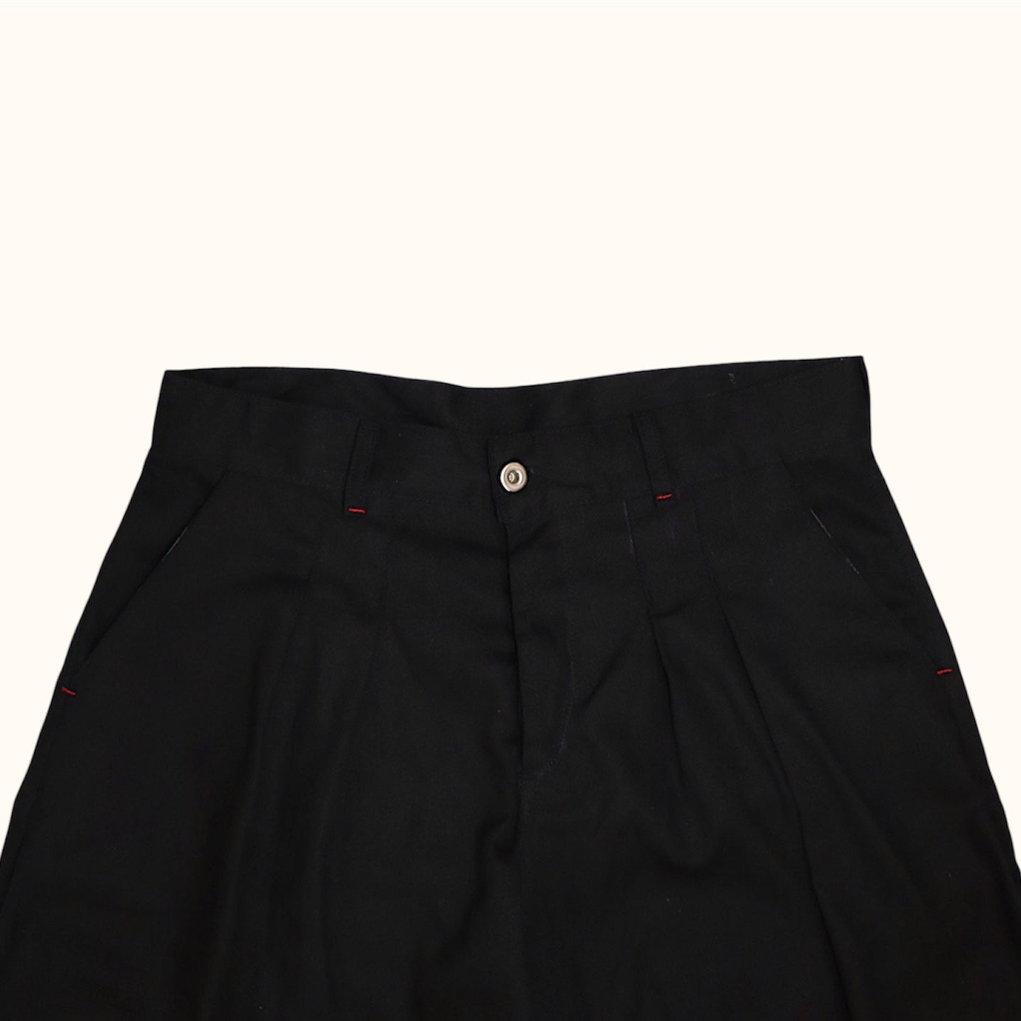 Close up of College Pleated Shorts showcasing red contrast stitching and a button closure.